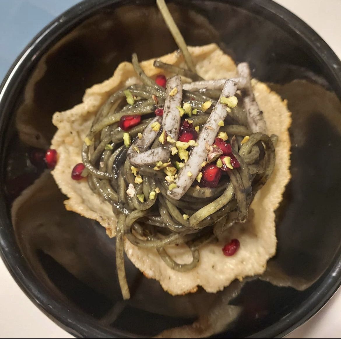 Pasta al nero di seppia con seppie scottate, melograno e granella di pistacchio