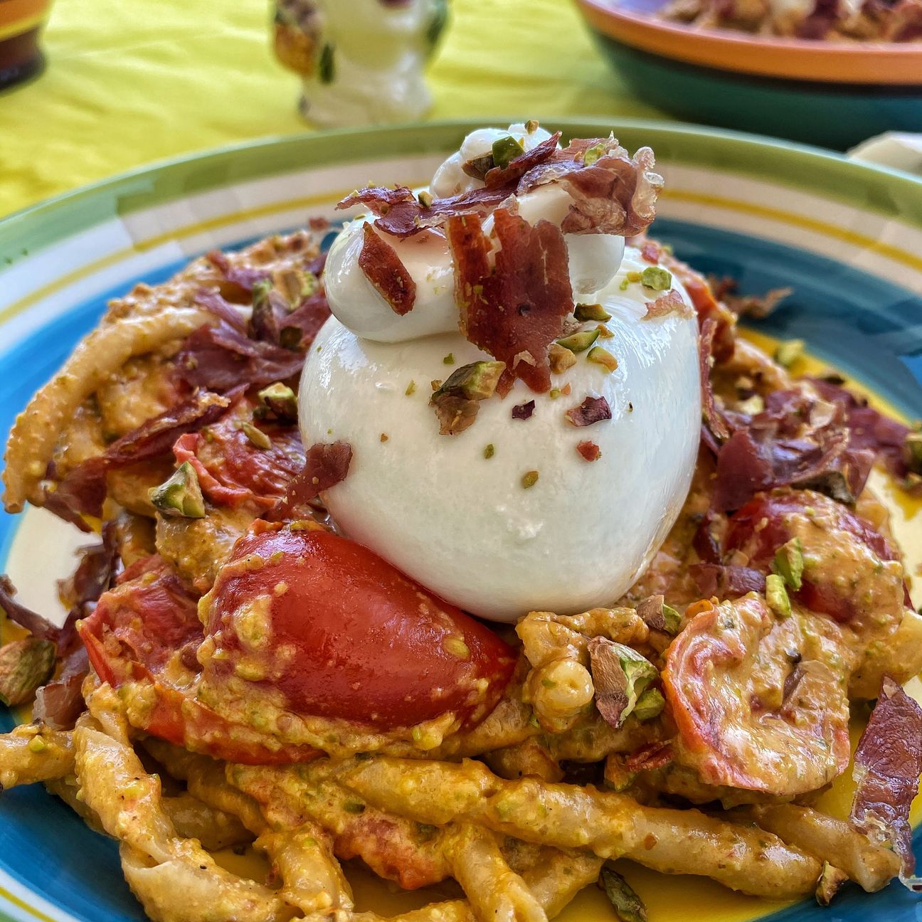 Busiate al pesto di pistacchio, pomodorini, burrata e scaglie di crudo