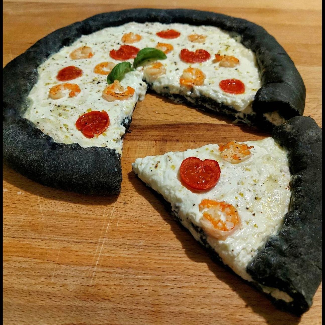 Pizza con impasto al nero di seppia, stracciatella e gamberetti con cornicione ripieno