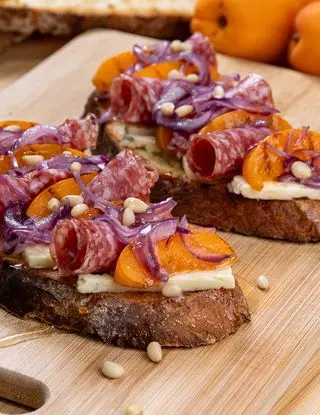 Ricetta Bruschetta con rose di salame, albicocche grigliate, cipolle caramellate, Edelblu Classic Bergader e pinoli di incucinafacendo