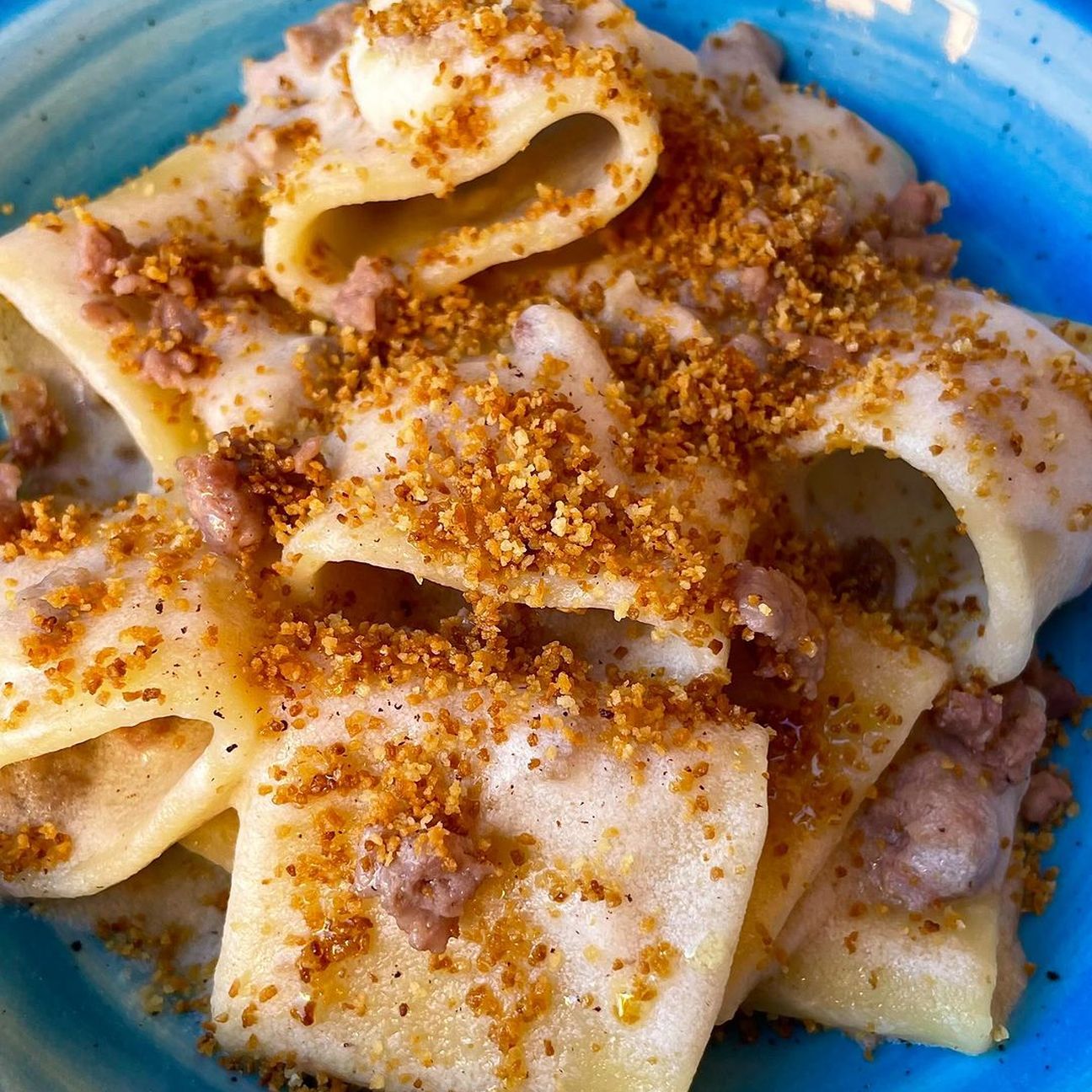Paccheri con crema al parmigiano al profumo di noce moscata, briciole di salsiccia croccante e pangrattato tostato