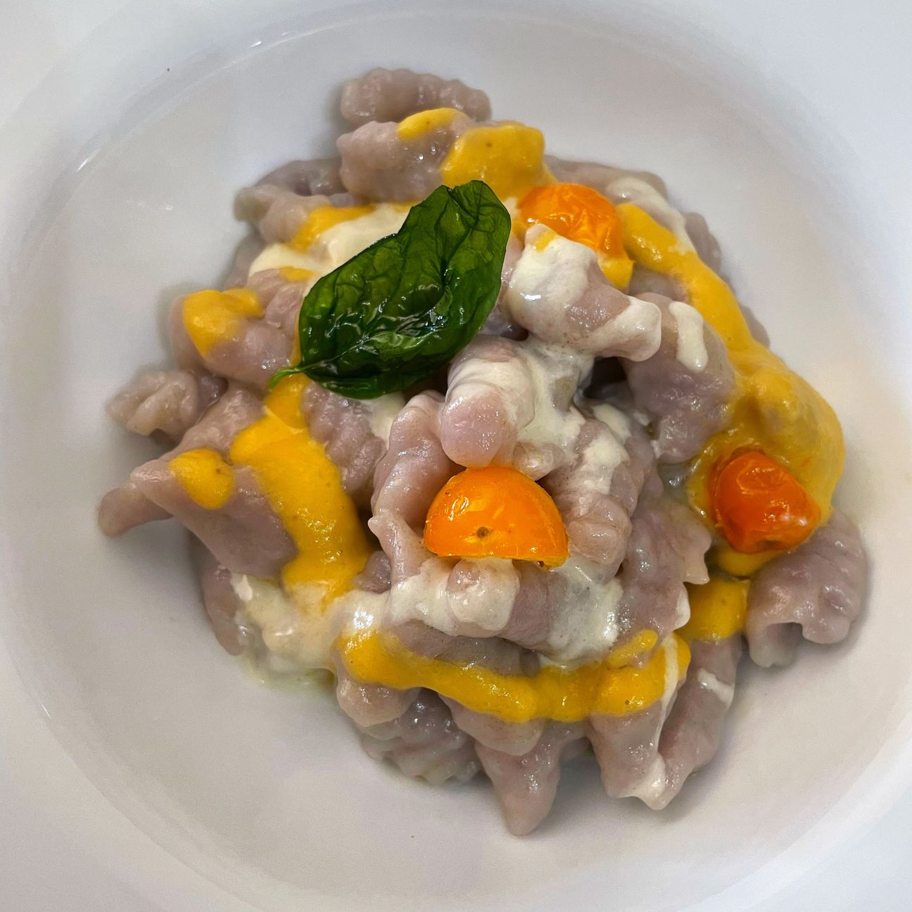 Gnocchi viola, salsa di datterino giallo, fonduta di parmigiano e cristallo di basilico