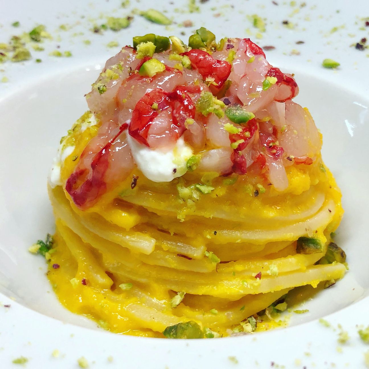 Chitarra con datterini gialli, gamberoni, gocce di burrata e crumble di pistacchi