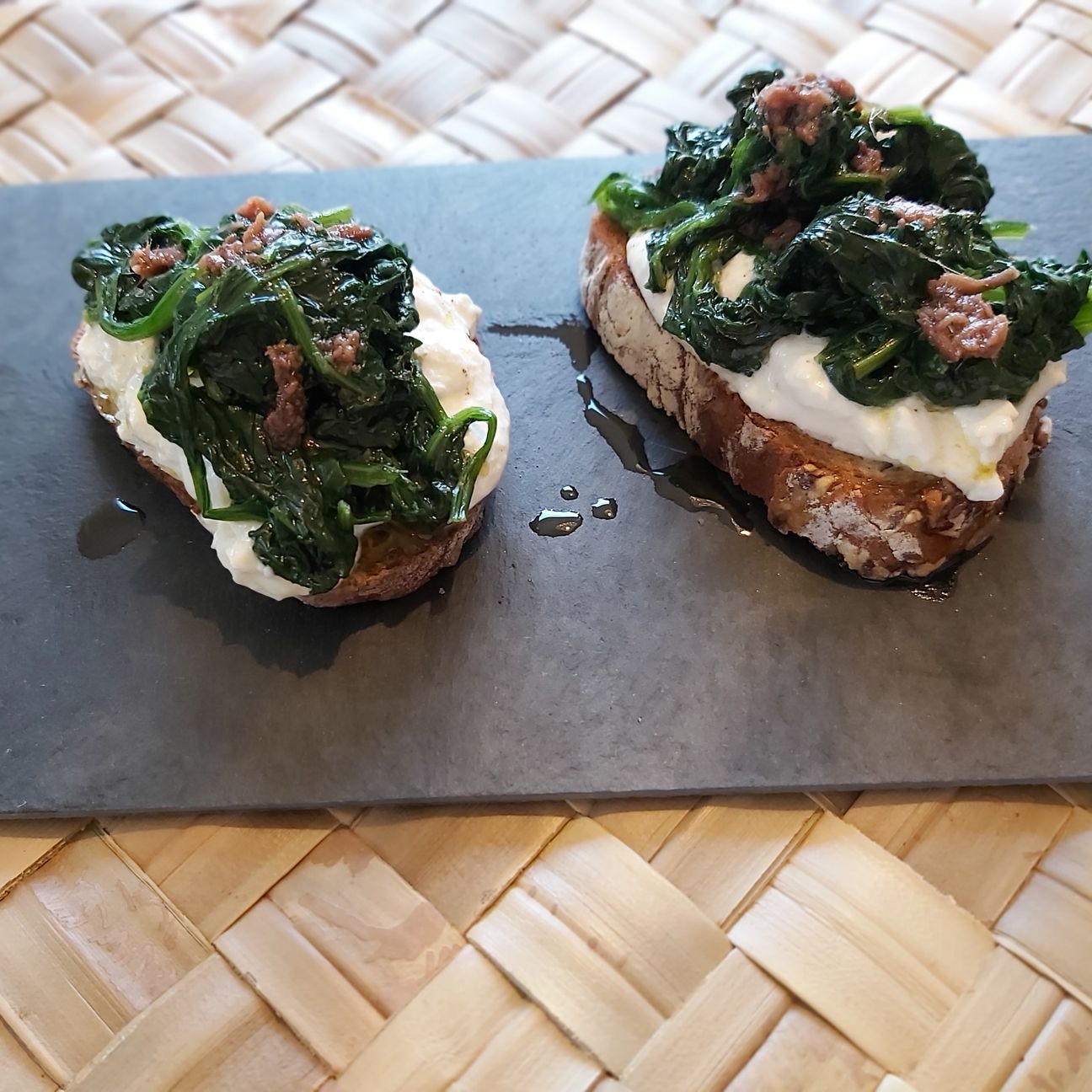 Crostoni ai cereali con burrata, spinacini e olio di acciughe