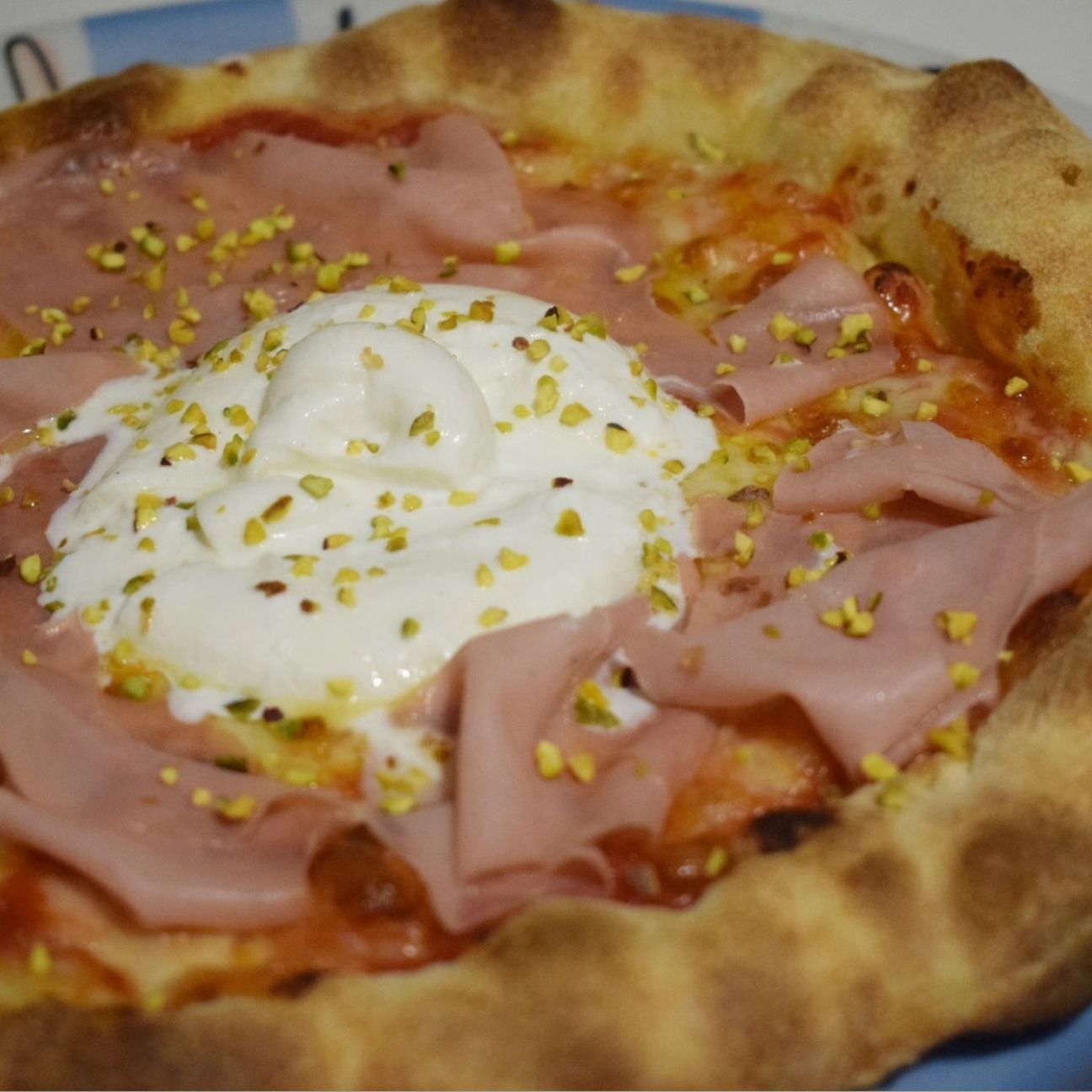 Pizza margherita con mortadella, burrata e granella di pistacchio.