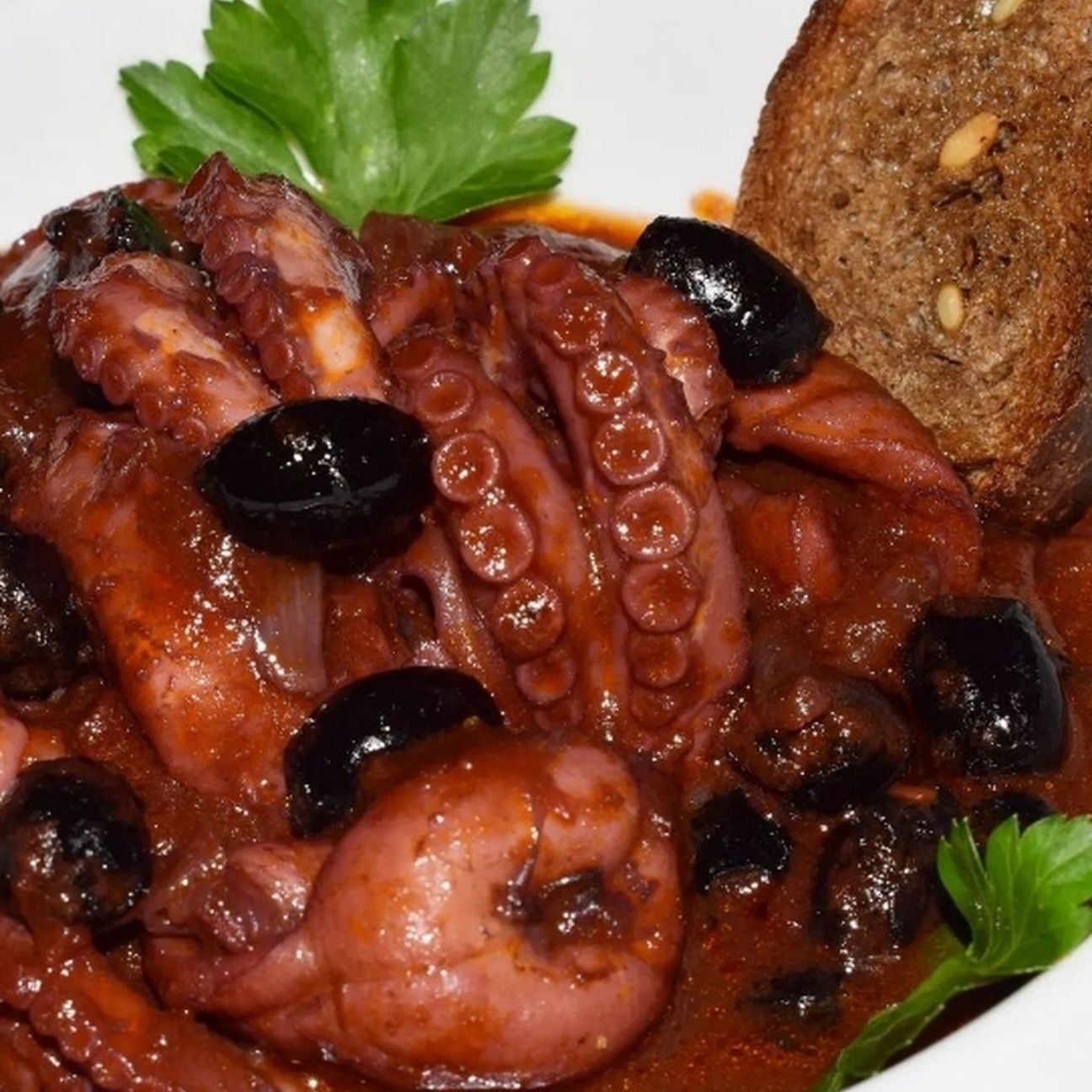 Moscardini affogati con olive celline e crostini di pane integrale ai cereali