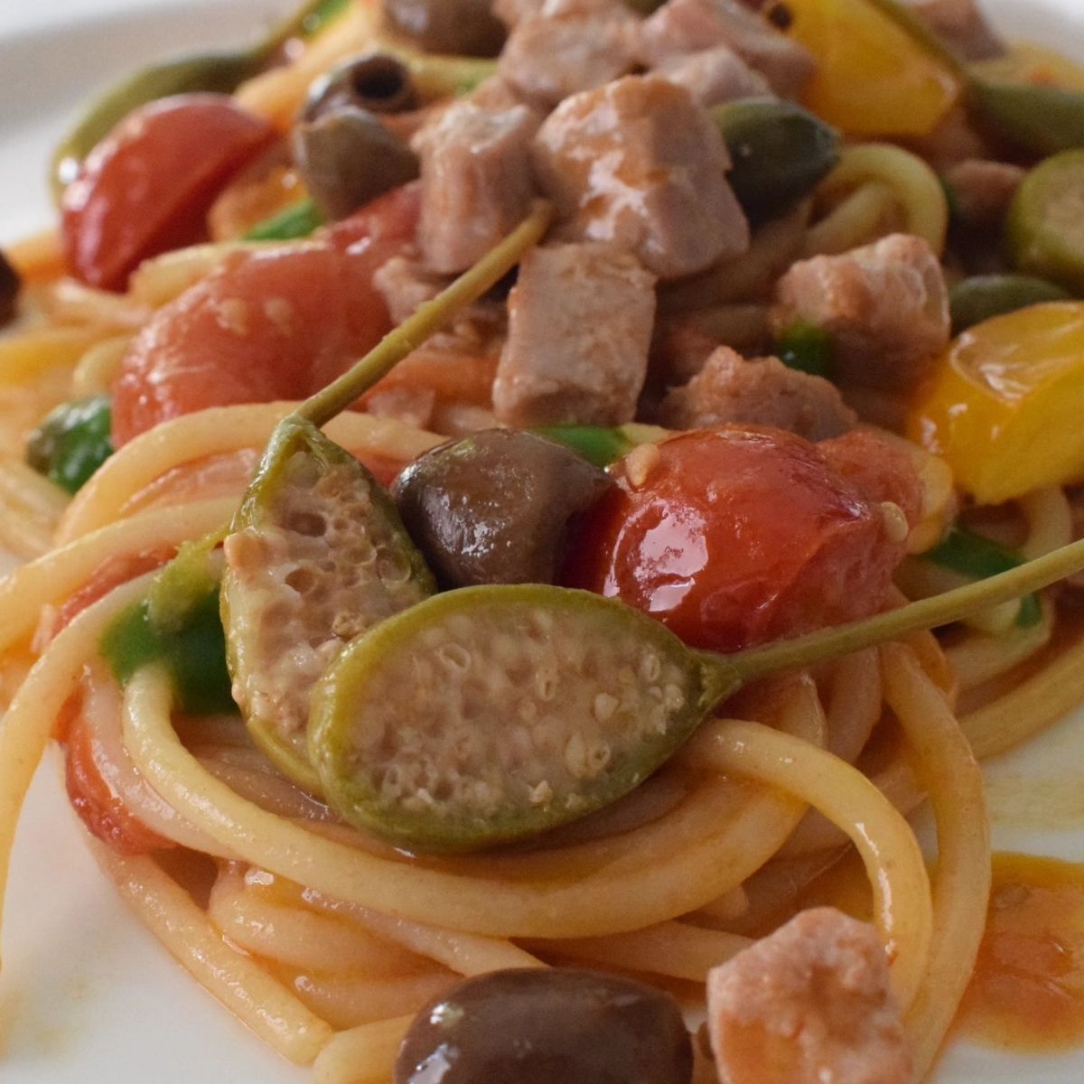 Spaghetti con tonno fresco, pomodorini, olive taggiasche e fiori di cappero.