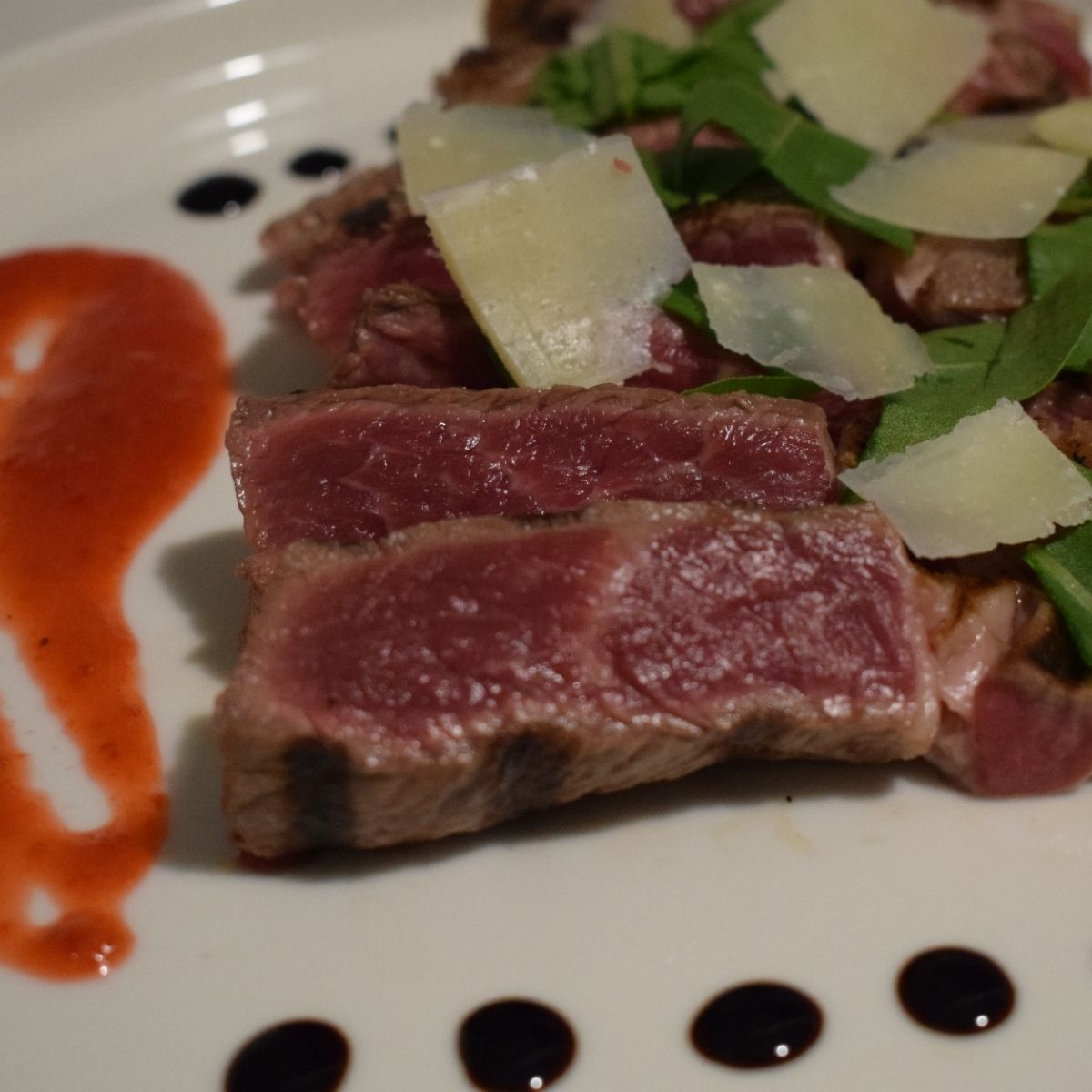 Scottona con rucola, parmigiano, salsa alle fragole e glassa all'aceto balsamico.