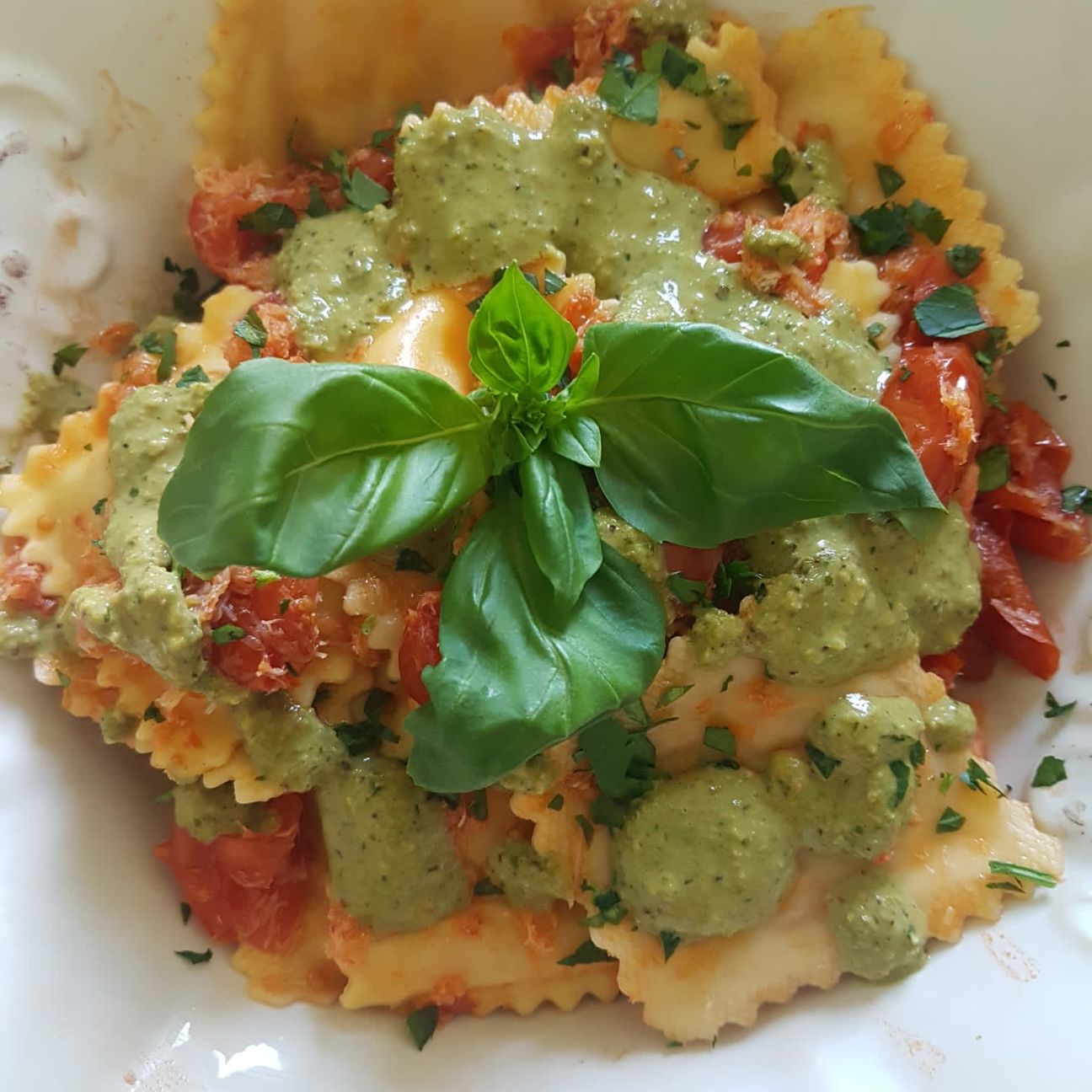 Ravioli ripieni di granchio reale con pomodorini e pesto di pistacchi