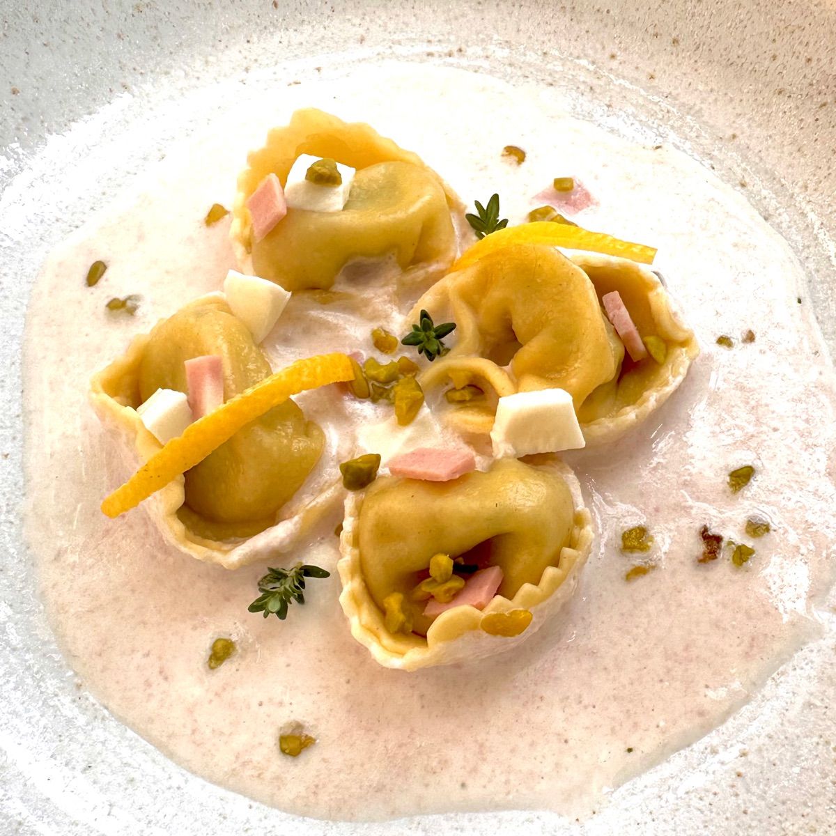 Tortelloni ricotta e spinaci con cremoso di mortadella e bufala, granella di pistacchio e limone candito