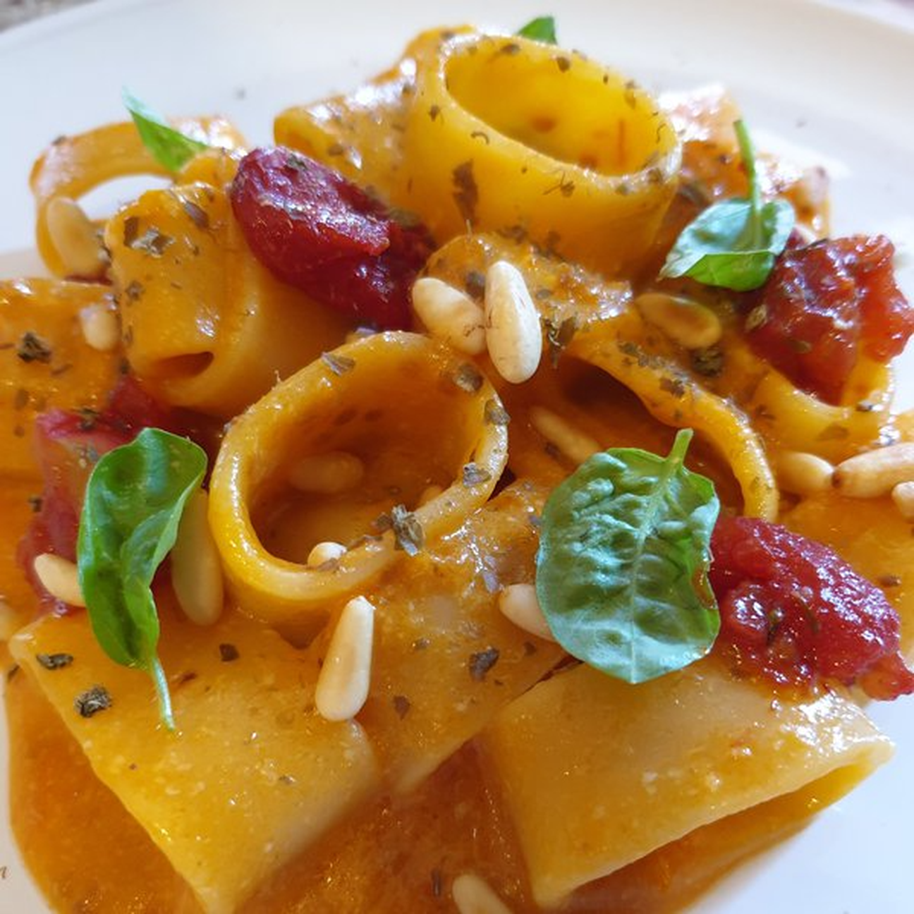 Calamarata in salsa di datterino giallo, pomodorini confit, basilico, pinoli tostati e polvere di capperi