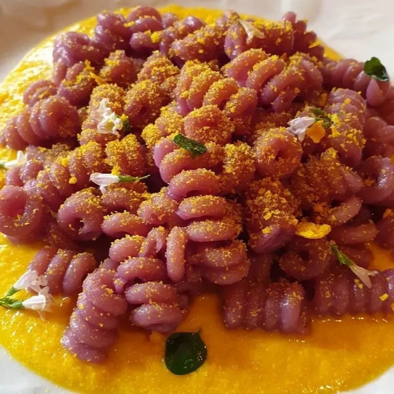 Fusilli bucati al cavolo viola su crema di parmigiano alla curcuma, granella di tarallo e fiori di mentuccia
