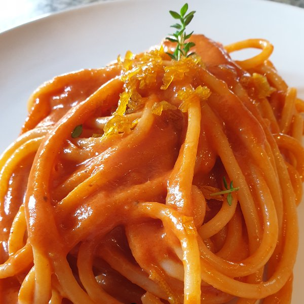 Spaghettoni mantecati con burro e alici, salsa di pomodori confit e scorze di limone caramellate