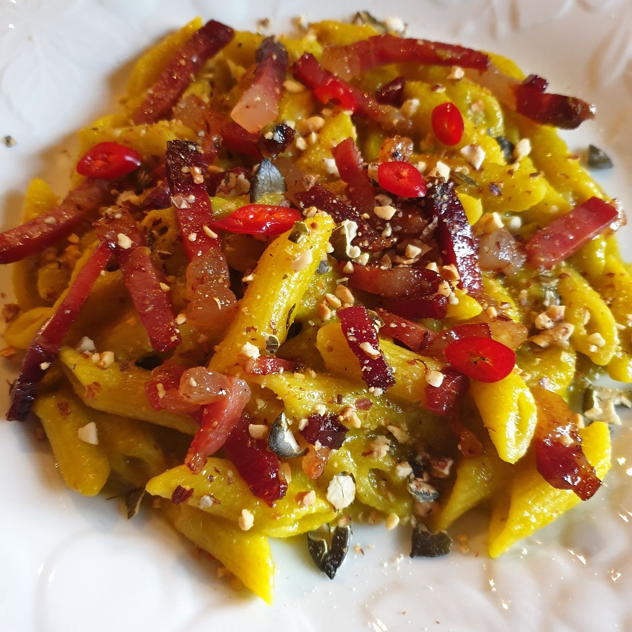 Mezze penne alla crema di zucchine e zafferano, speck croccante, frutta secca e peperoncino fresco