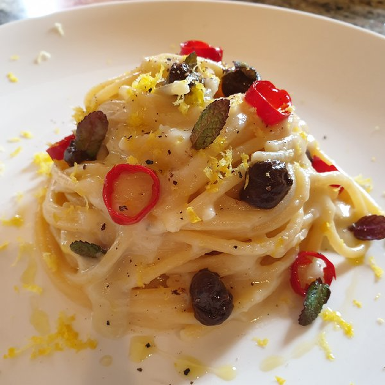 Spaghettoni in salsa di topinambur, crema di aglio nero, peperoncino croccante, menta fresca e scorza di limone