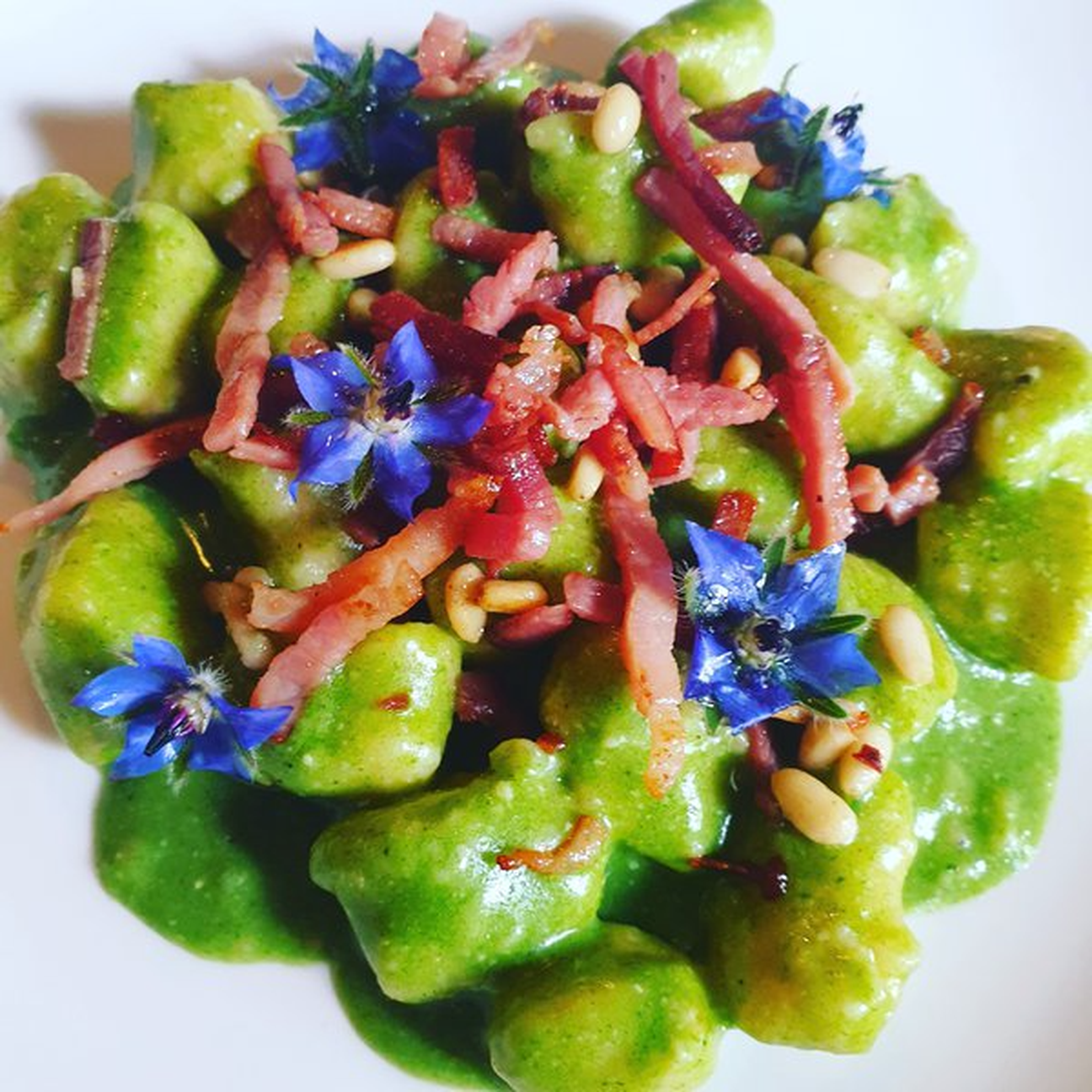 Gnocchi di polenta al pesto di borragine, speck croccante e pinoli tostati