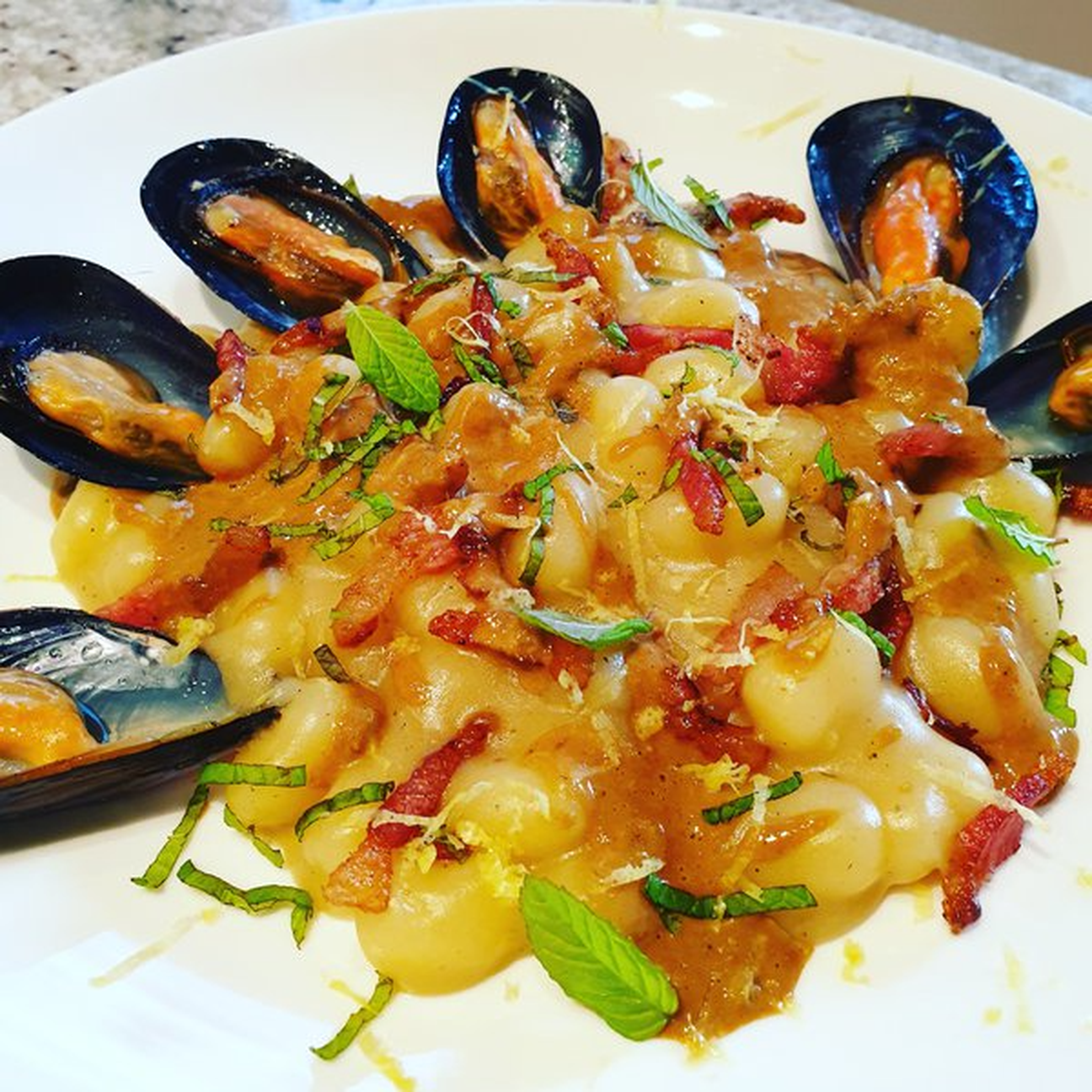 Chicche alle cozze con crema di cipollotto grigliato, guanciale croccante, menta e zenzero grattugiato