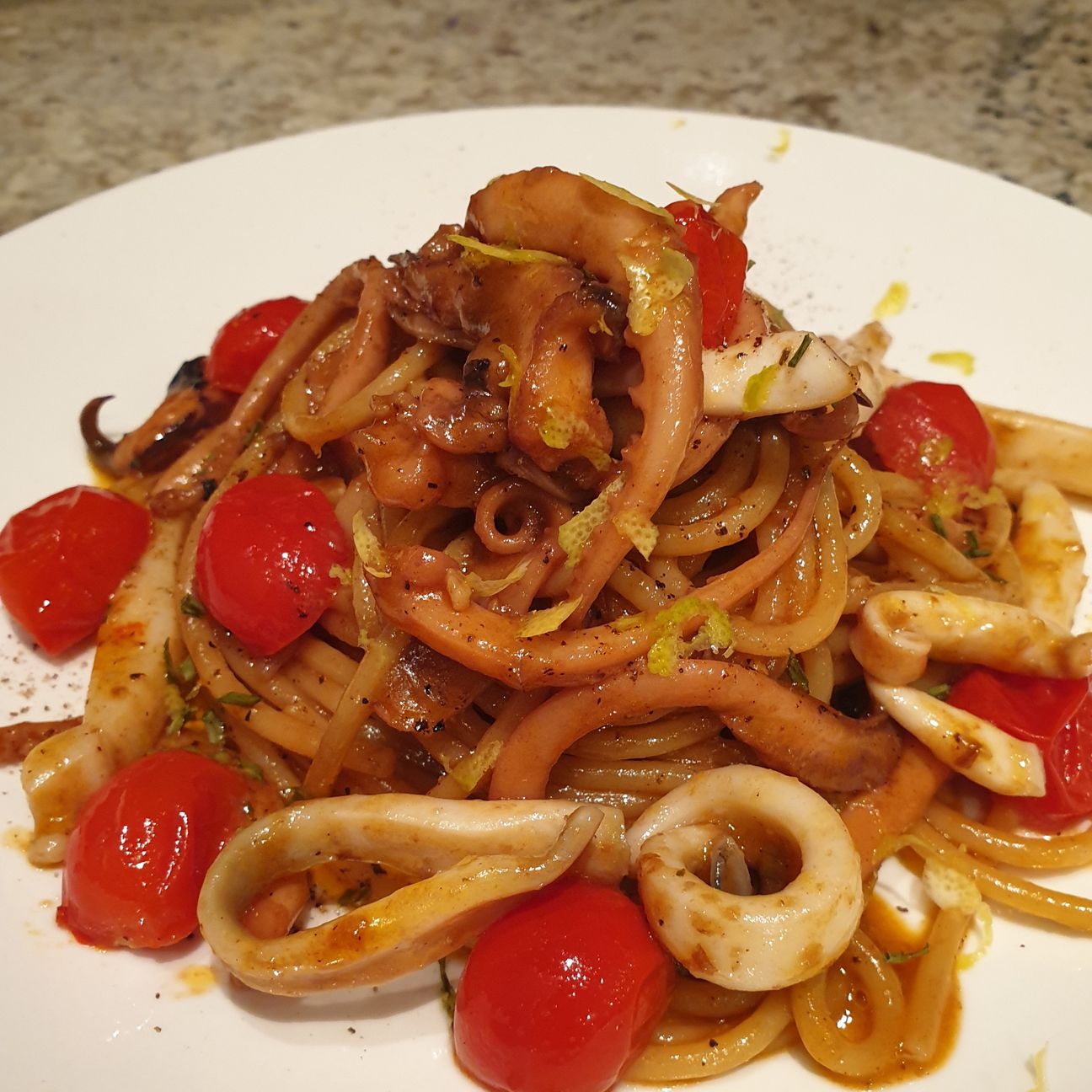 Spaghettoni ai calamari e seppie con pomodorini brasati, scorzetta di limone e erba cipollina