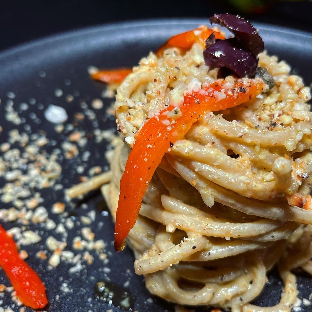 Spaghetti con crema di peperoni, olive, capperi e granella di mandorle tostate