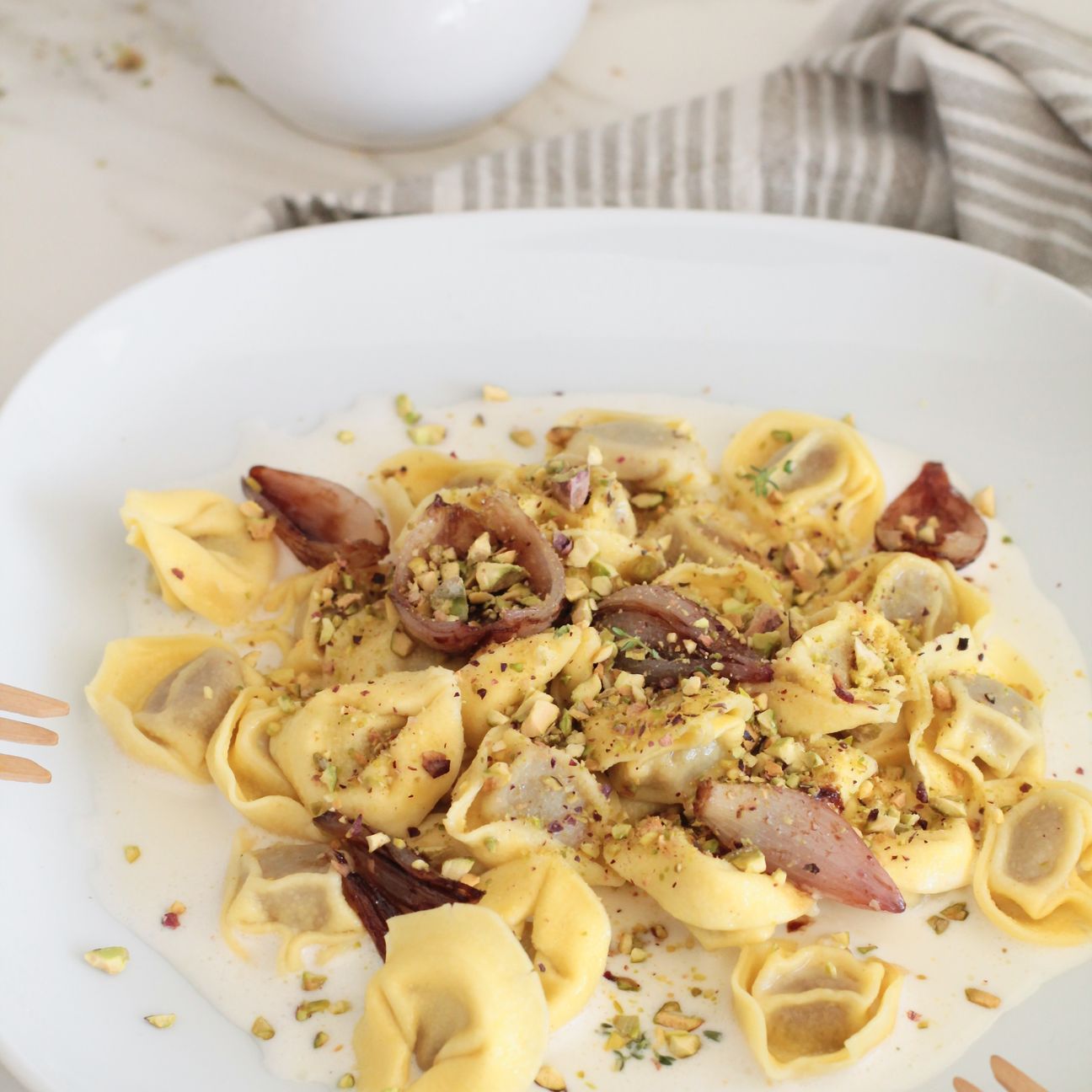 Tortellini alla carne con crema di taleggio, scalogno caramellato e pistacchi