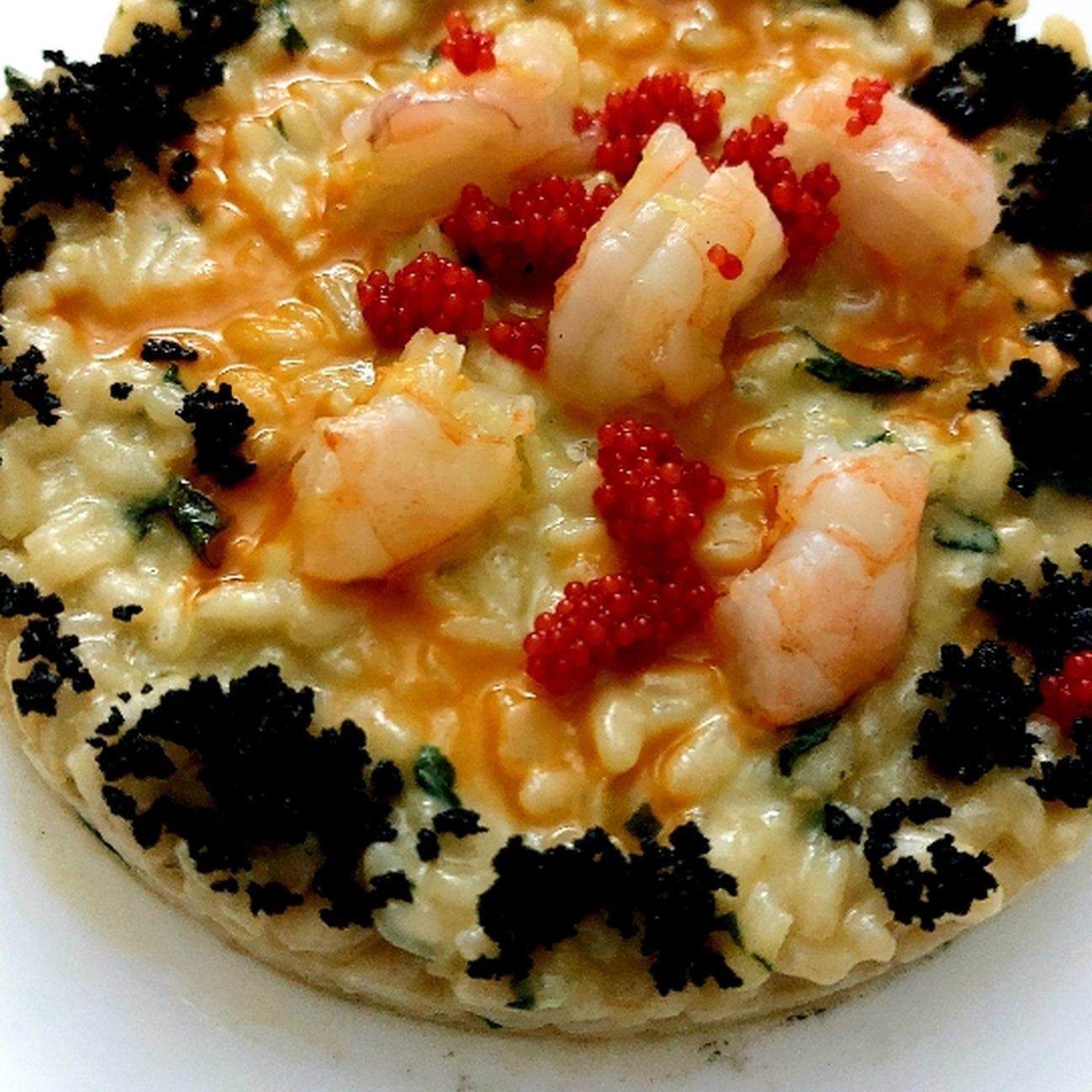Risotto al pesto gentile con gamberi, polvere di nero di seppia e uova di lombo