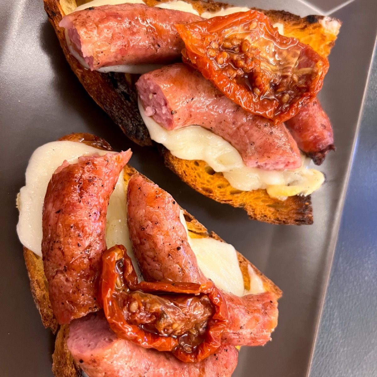 Bruschette con salsiccia alla griglia, pomodori secchi e caciocavallo impiccato