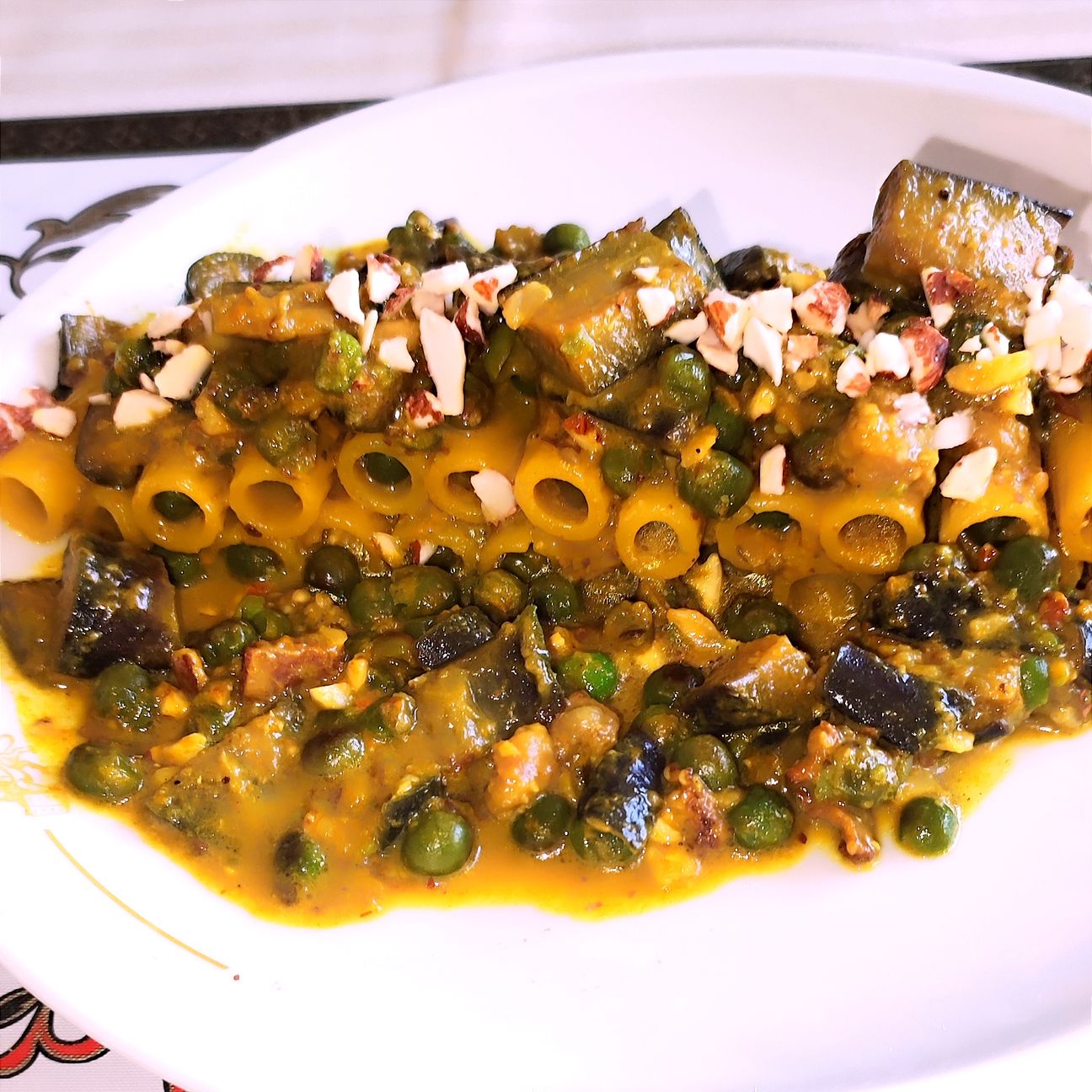 Rigatoni con piselli melanzane e granella di mandorla in crema di zafferano.
