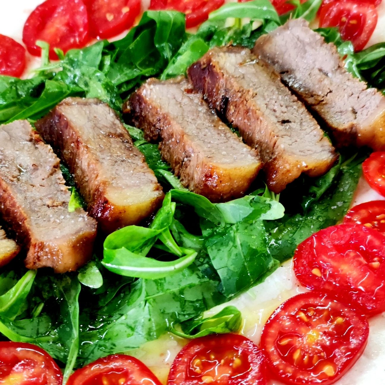 Tagliata di bovino su letto di rucola e pomodori.
