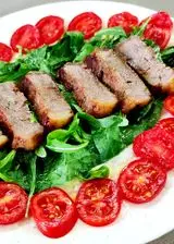 Ricetta Tagliata di bovino su letto di rucola e pomodori.