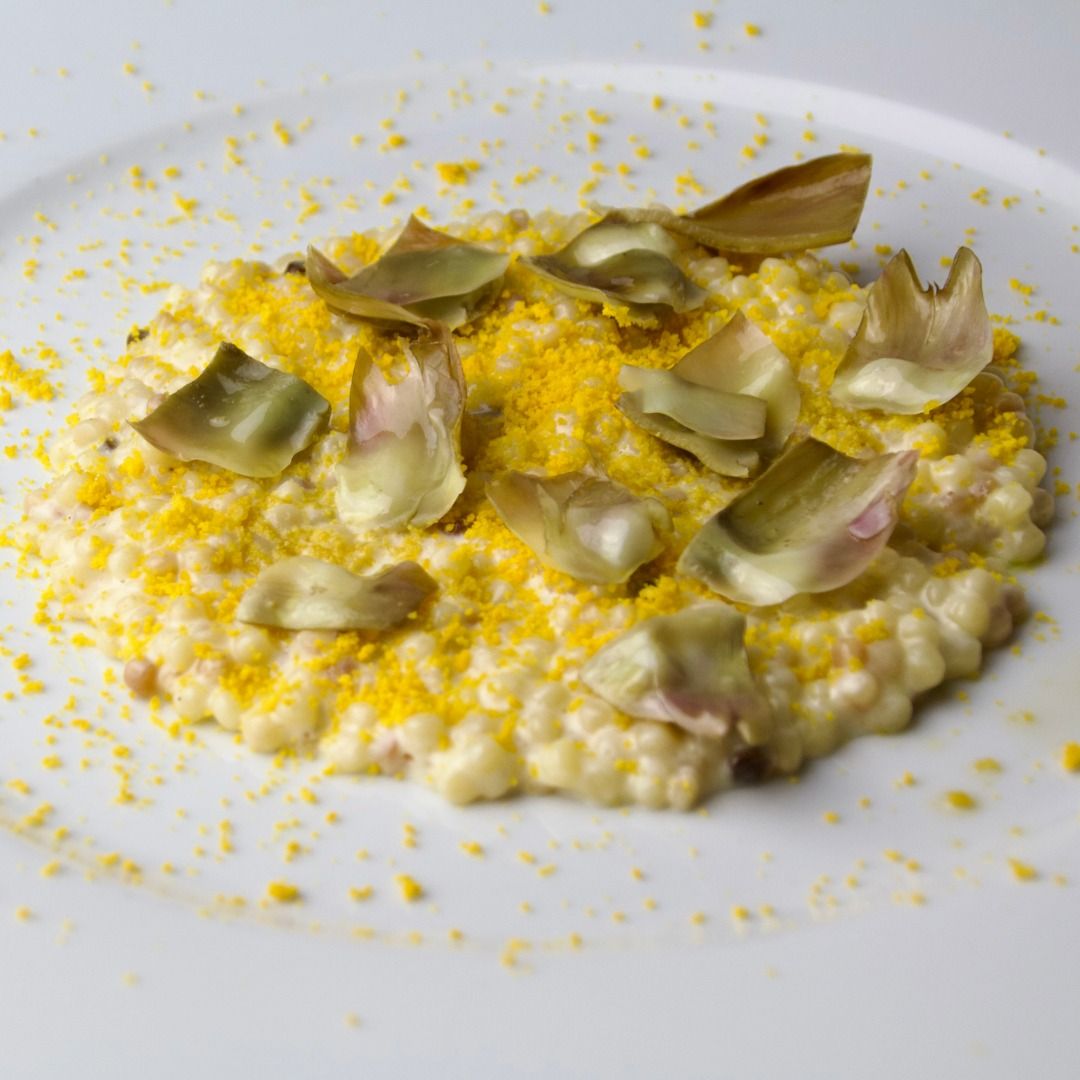 Fregola risottata con fonduta di Parmigiano Reggiano, carciofi saltati e polvere d'uovo disidratato