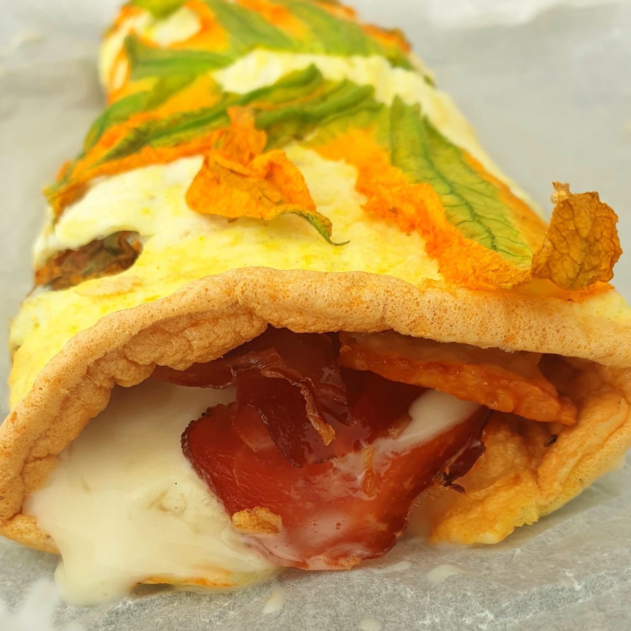 Rotolo in fiore: rotolo di albumi alla curcuma, avvolto con fiori di zucca e ripieno con speck e provola