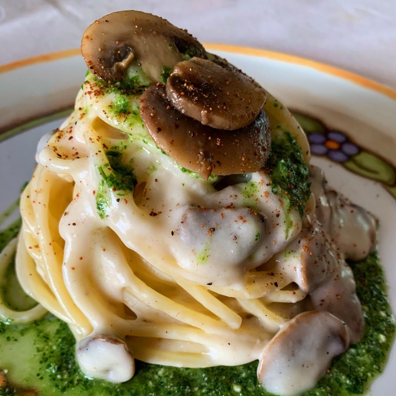 Spaghettoni ai funghi champignon, avvolti da crema al parmigiano e pesto di rucola, con una spolverata di noce moscata.