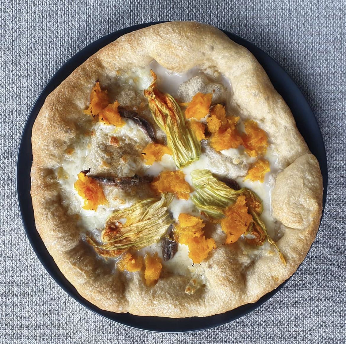 Pizza gourmet con mozzarella, zucca, fiori di zucca e acciughe