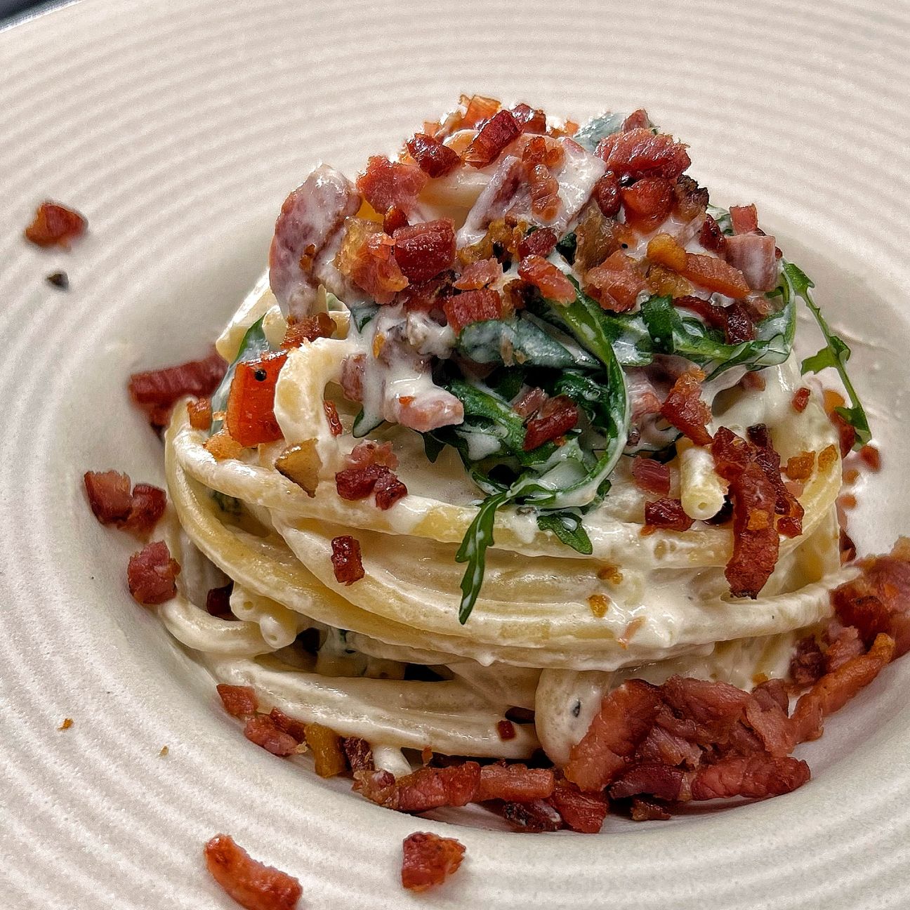 Bucatini con crema di robiola, speck croccante e rucola