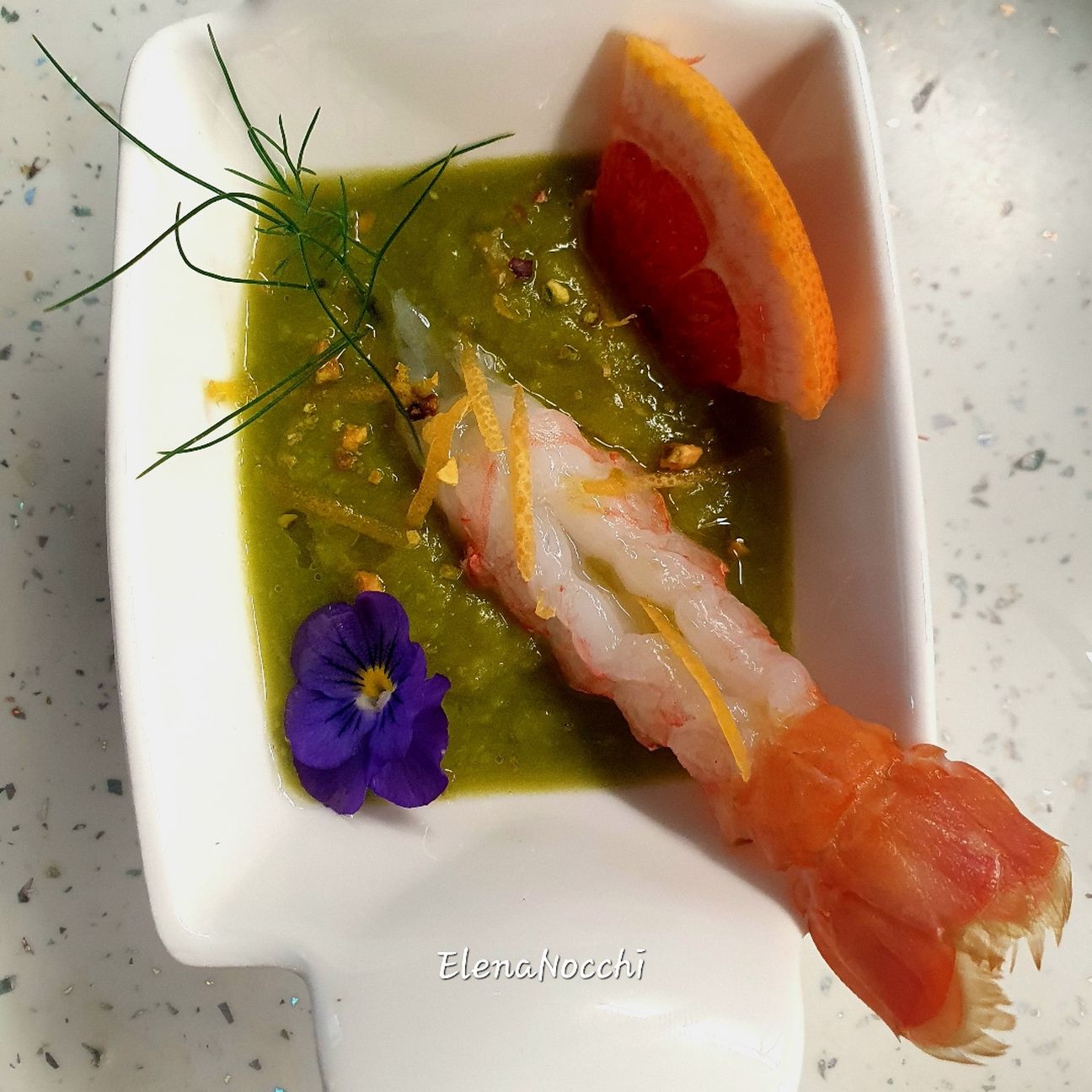 Crema di piselli con scampo marinato al pompelmo rosa, le sue scorzette e granella di pistacchio
