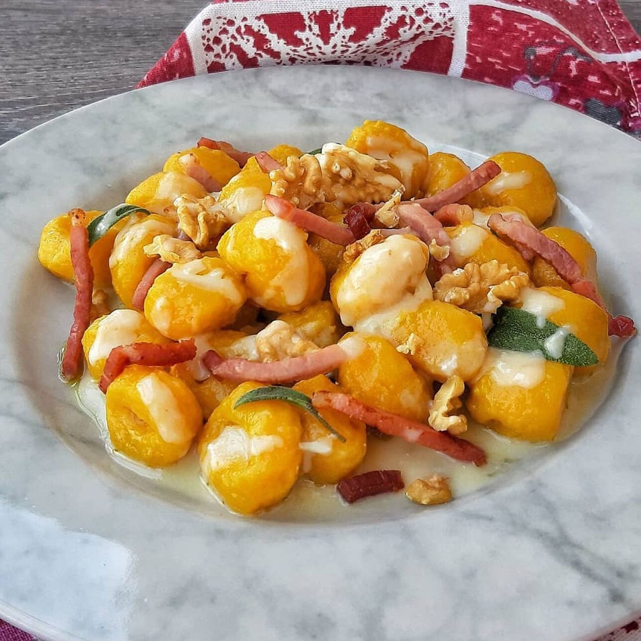 Gnocchi di zucca con olio alla salvia, fonduta di Gorgonzola e Parmigiano, noci e speck croccante
