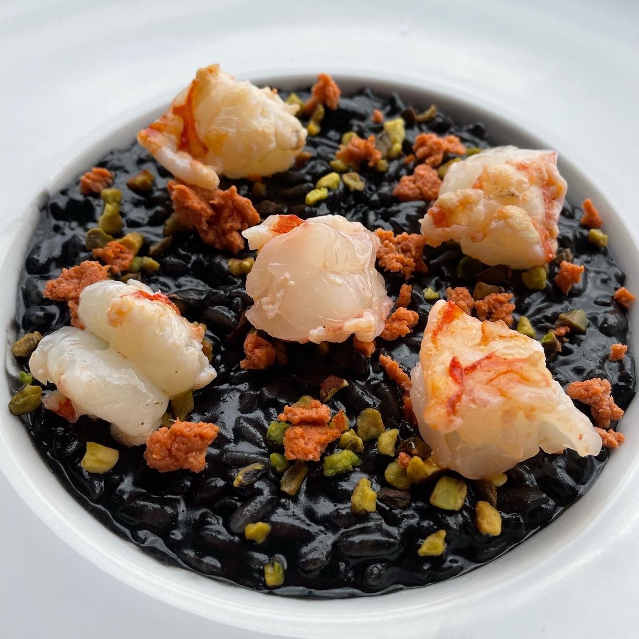 Risotto al nero di seppia con granella di pistacchi, stracciatella di gamberi e gambero scottato🔥🌊