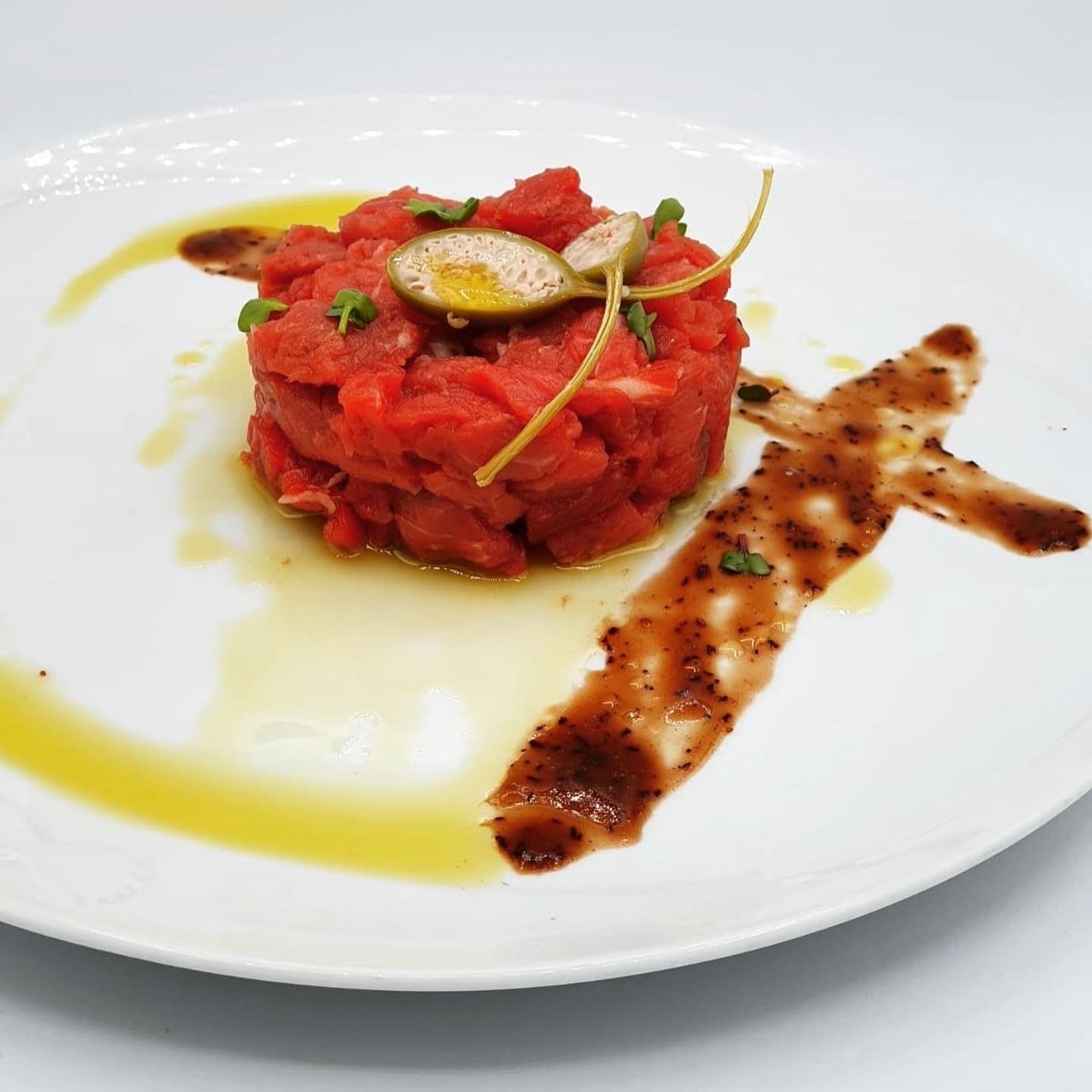 Tartare di manzo affumicata al legno di quercia con frutto del cappero e salsa di mirtilli