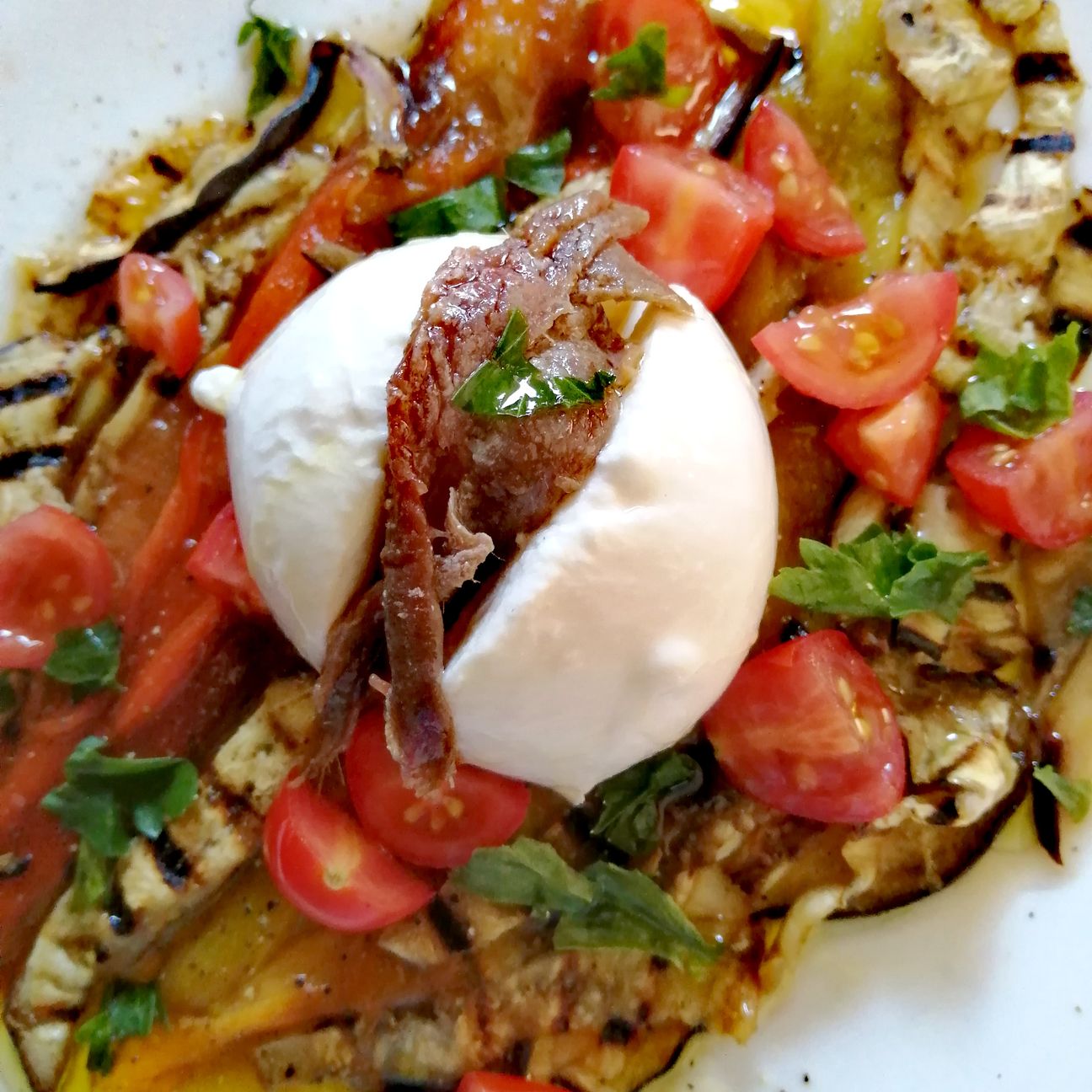 Peperoni e melanzane arrostite condite con pomodorini, mozzarella e alici.