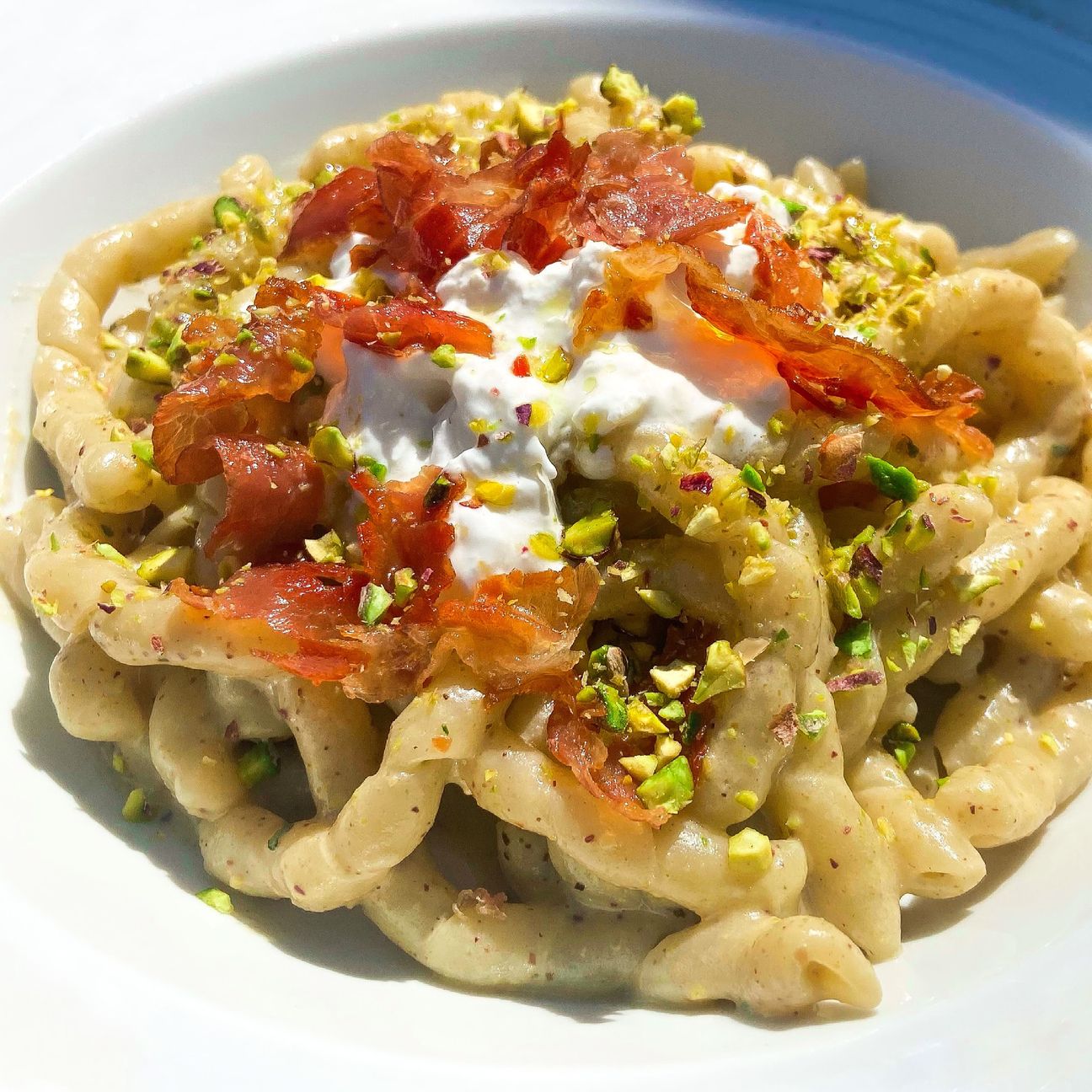Busiate con crema di pistacchi, stracciatella e crudo di Parma croccante.