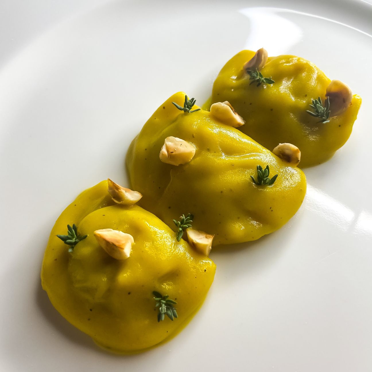 Mezzelune di zucca con crema di patate alla curcuma, timo e nocciole tostate