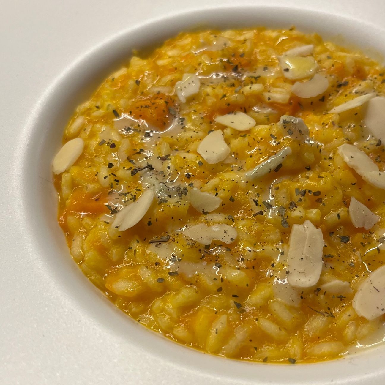 Risotto mantecato al burro e grana padano con crema di carote, gorgonzola e scaglie di mandorle