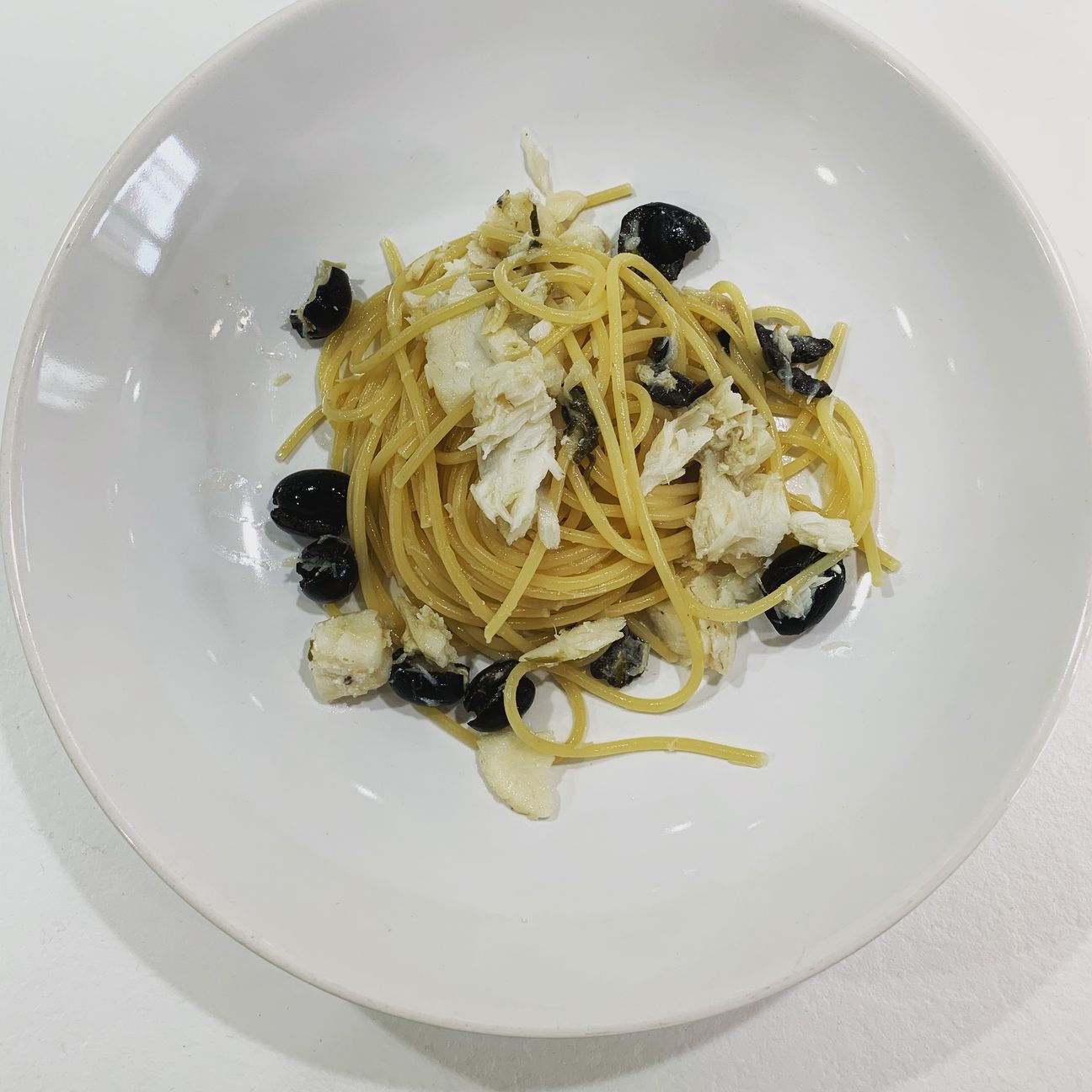 Spaghetti con filetti di merluzzo olive nere e capperi