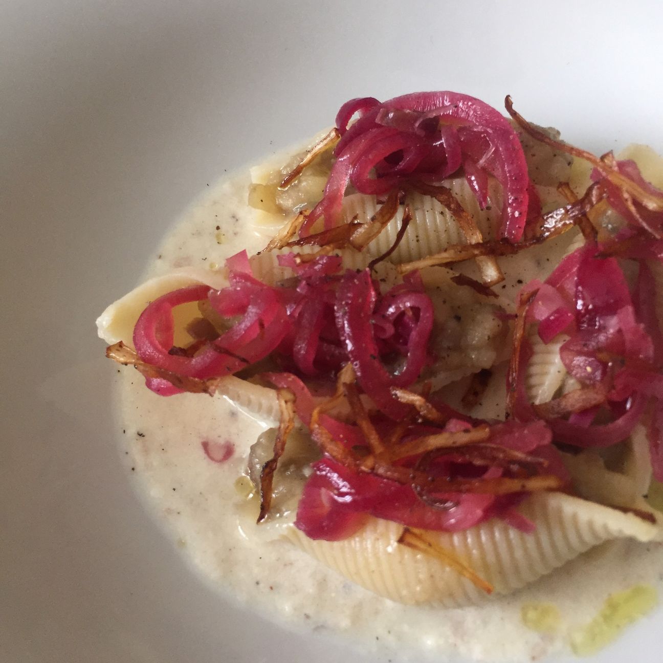 Conchiglioni ripieni di melanzane e patate su crema di parmigiano, accompagnati da cipolle caramellate