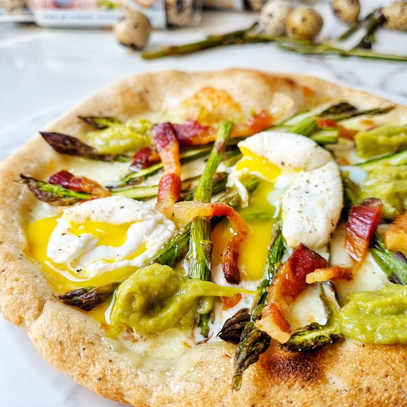 Pizza primavera con uova di quaglia in camicia, asparagi e guanciale croccante