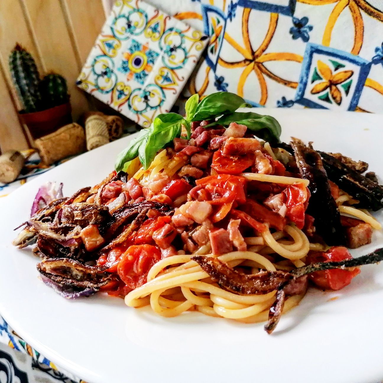 Spaghetti con pomodori confit, pancetta croccante e cipolla fritta