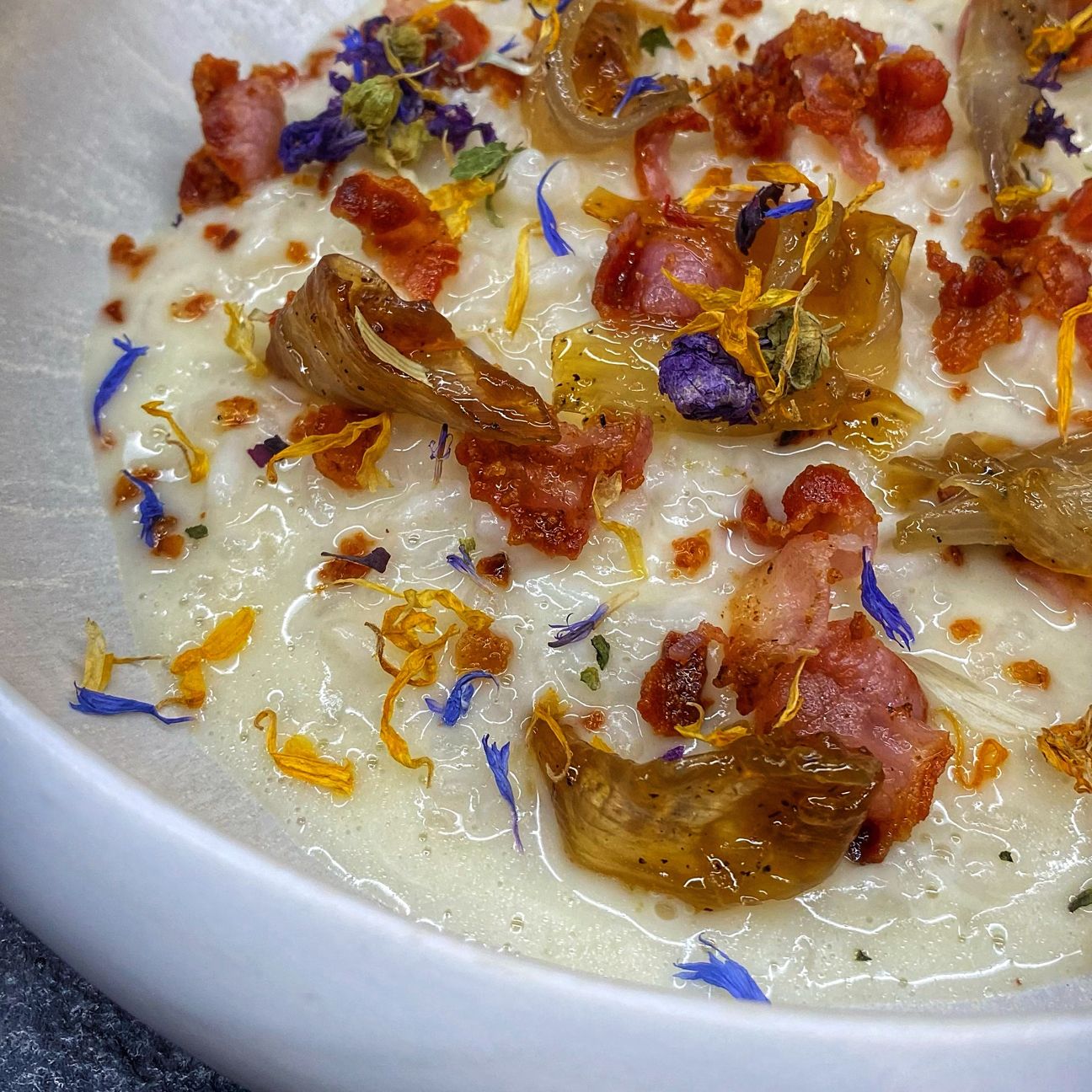 Risotto cremoso con stracchino, petali di scalogno caramellato e bacon croccante