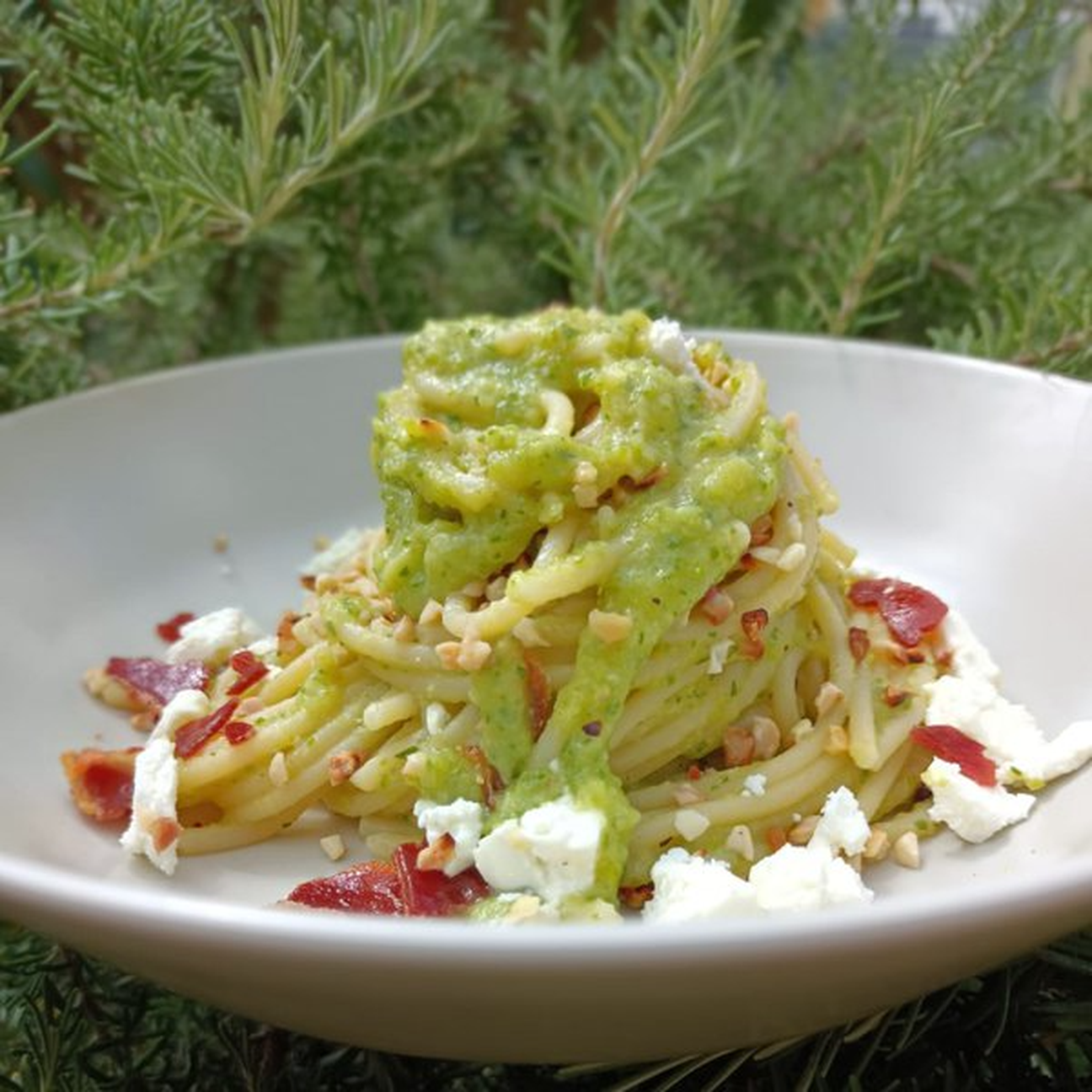 Spaghetti con crema di zucchine feta briciole di speck e granella di mandorle .