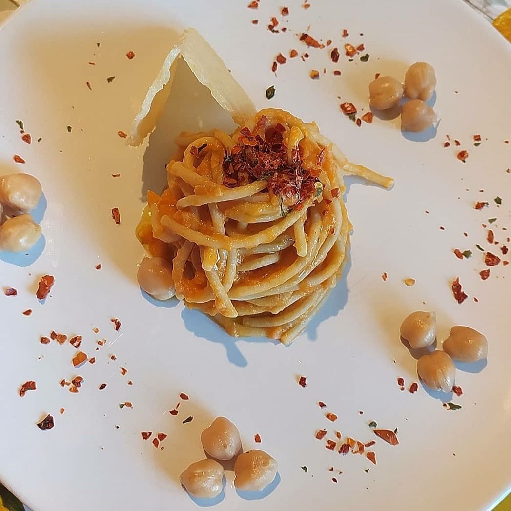 Spaghetti integrali con crema di zucca e ceci, peperone dolce e cialda di parmigiano.