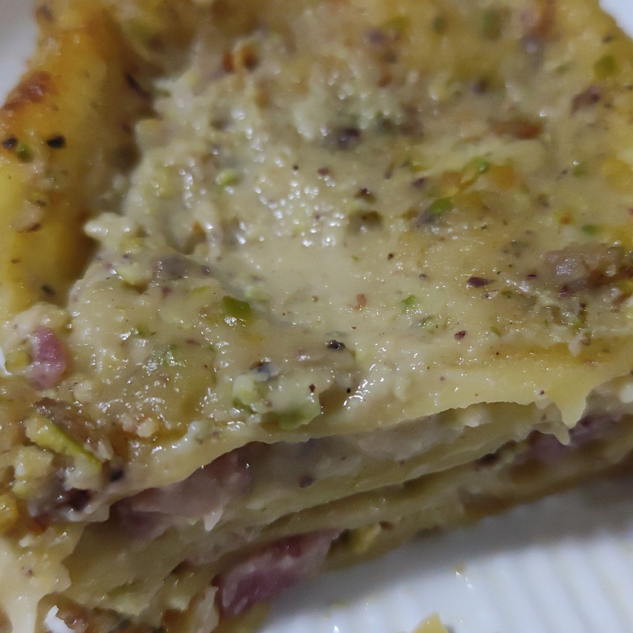 Lasagne fresche con besciamella al pistacchio, pancetta, mozzarella, scamorza bianca e granella di pistacchi.